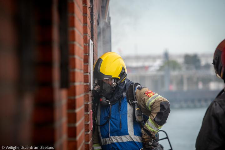 Brandweerman met ademlucht bij de gevel