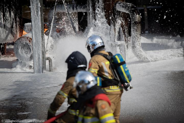 Brandweerploeg in het schuim bij een industriebrand