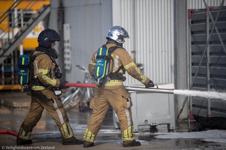 Twee brandweerlieden met een straal bij de installatie