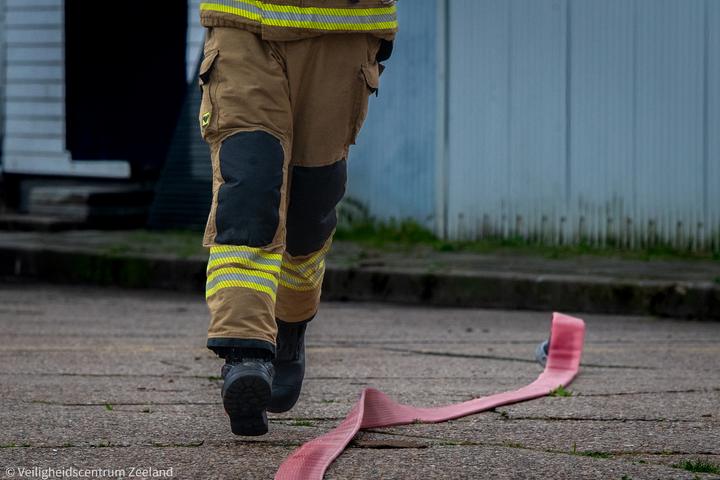Brandweerman rolt een slang uit